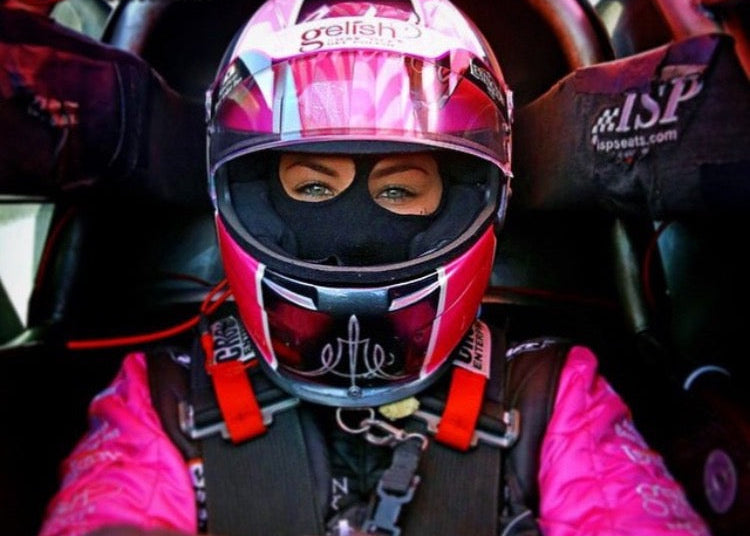 Person in a racing suit and helmet inside a vehicle, with visible branding.